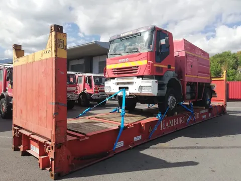 Arrimage d'un camion de pompiers IVECO sur un conteneur flat rack avec sangles pour l'expédition maritime — IFTL