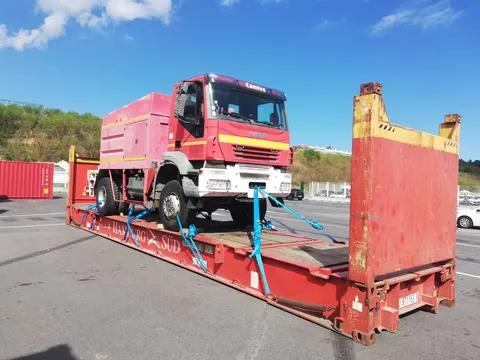 Camion de pompiers Camiva arrimé sur un flat rack Hamburg Sud avant expédition maritime — IFTL