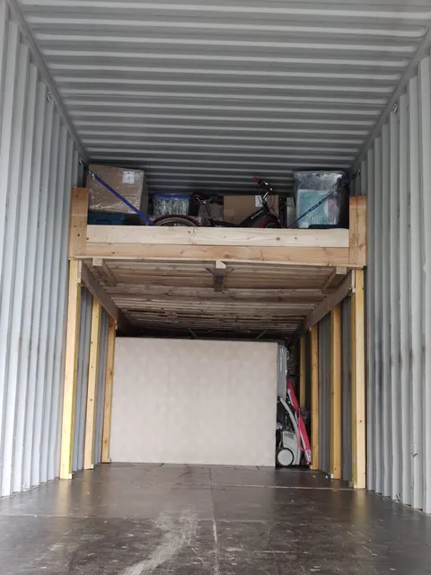 Effets personnels et vélos arrimés par sangles sur une mezzanine en bois dans le conteneur maritime — IFTL