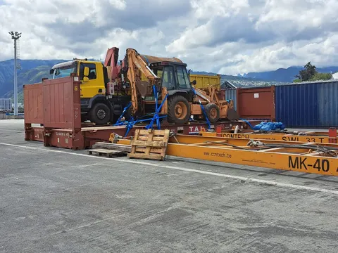 Tractopelle et camion benne arrimés sur des flat racks avant transport maritime — IFTL
