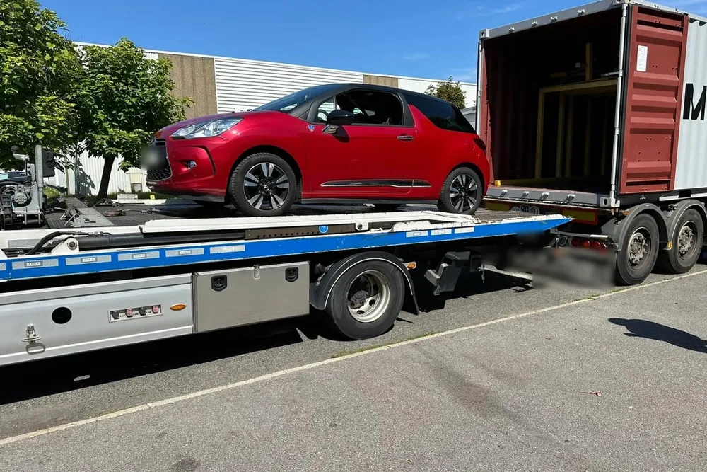 Chargement & dépôt, conteneur resté sur son châssis routier au dépôt de Paris, une dépanneuse-plateau amène une voiture à hauteur du plancher — chantier réel IFTL
