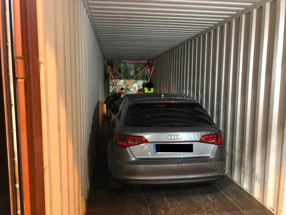 Chargement & dépôt, voiture chargée en dernier, côté portes d’un conteneur 40 pieds, devant les effets personnels sanglés en X — chantier réel IFTL