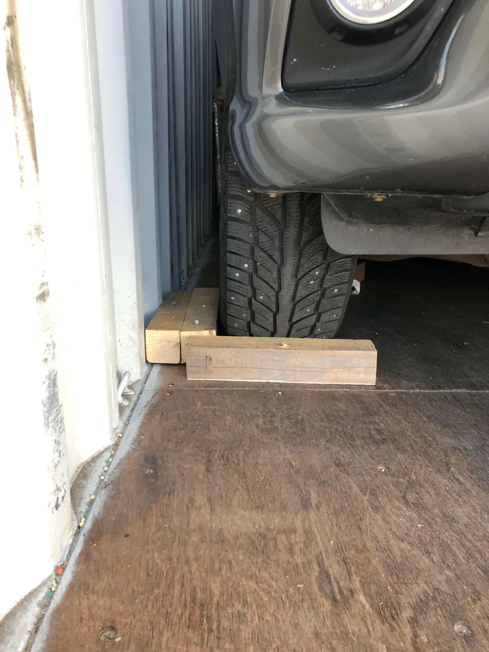Arrimage véhicule, roue calée par des tasseaux en bois sur le plancher du conteneur — chantier réel IFTL