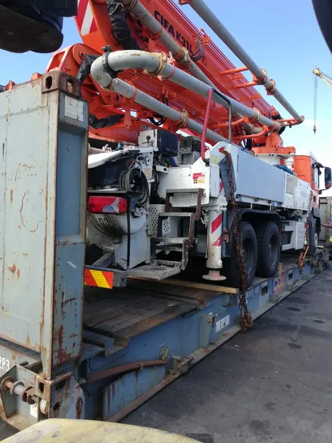 Pompe à béton CIFA K31L arrimée en hors gabarit sur un flat rack avant expédition — IFTL