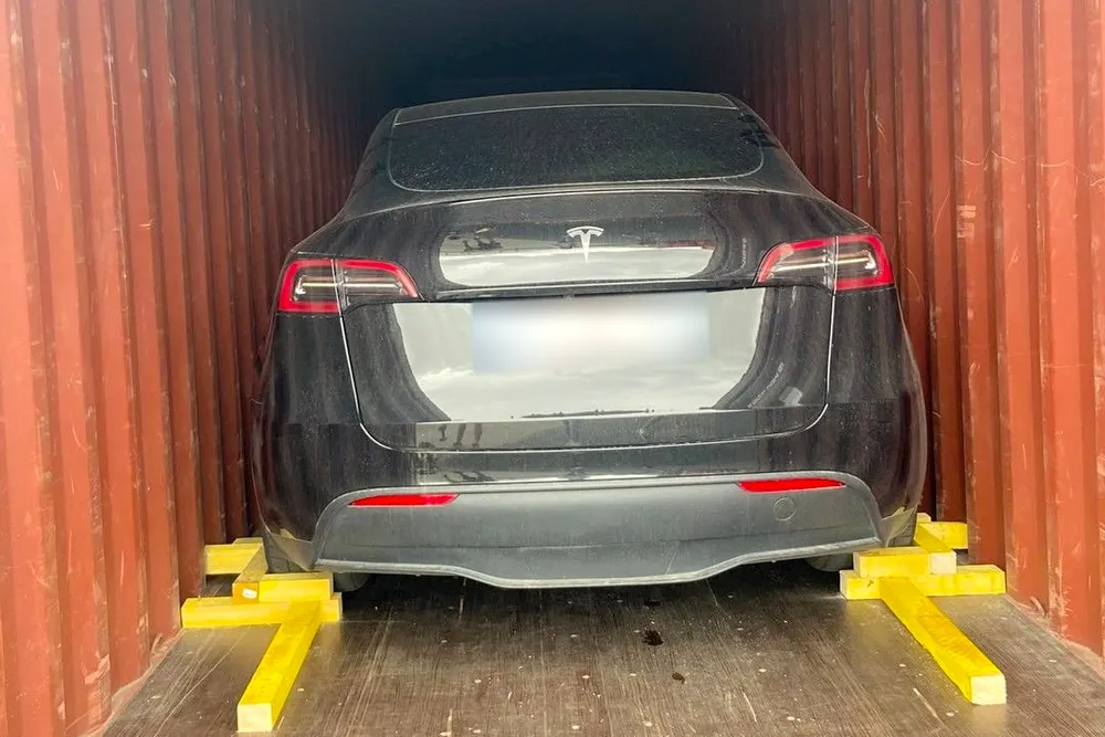 Voiture électrique immobilisée par des cales en bois dans un conteneur — IFTL