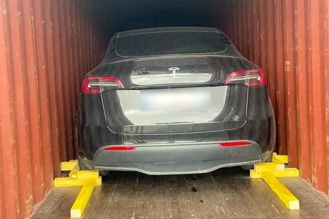 Voiture électrique immobilisée par des cales en bois dans un conteneur — IFTL