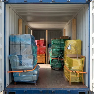 Conteneur partagé : les meubles et les cartons de plusieurs clients, chaque lot filmé à part — image d’illustration